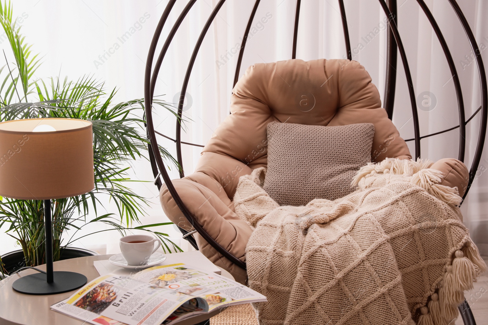 Photo of Comfortable place for rest with hanging chair near window in room