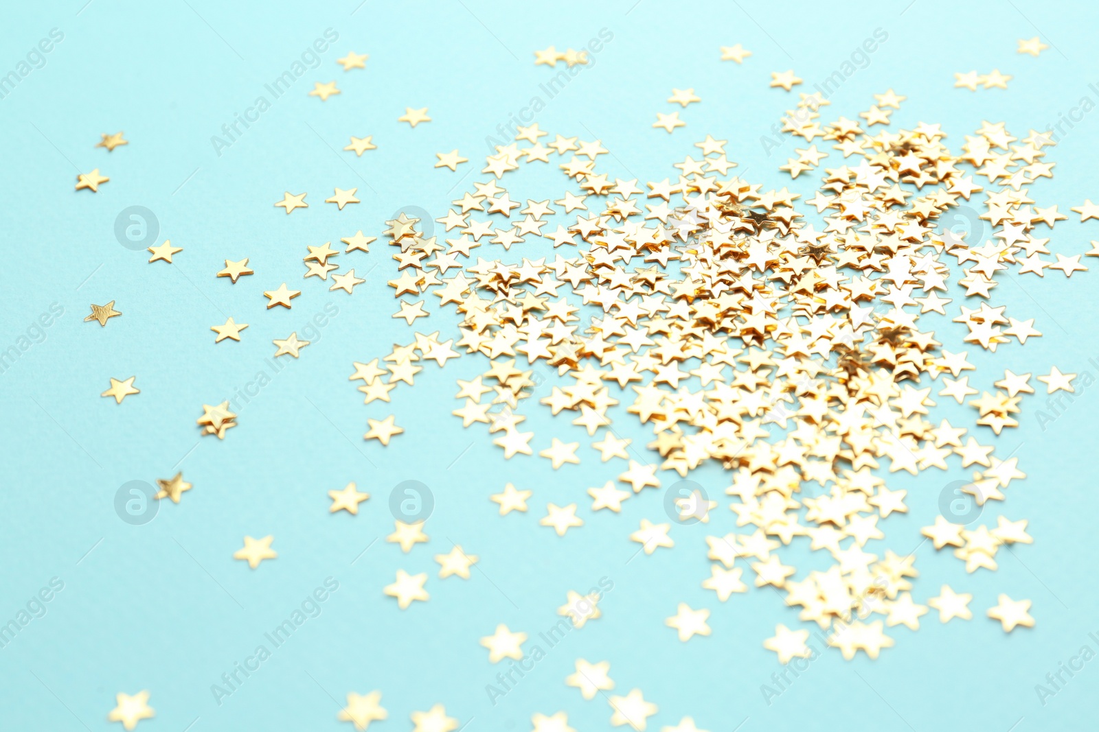 Photo of Confetti stars on light blue background. Christmas celebration