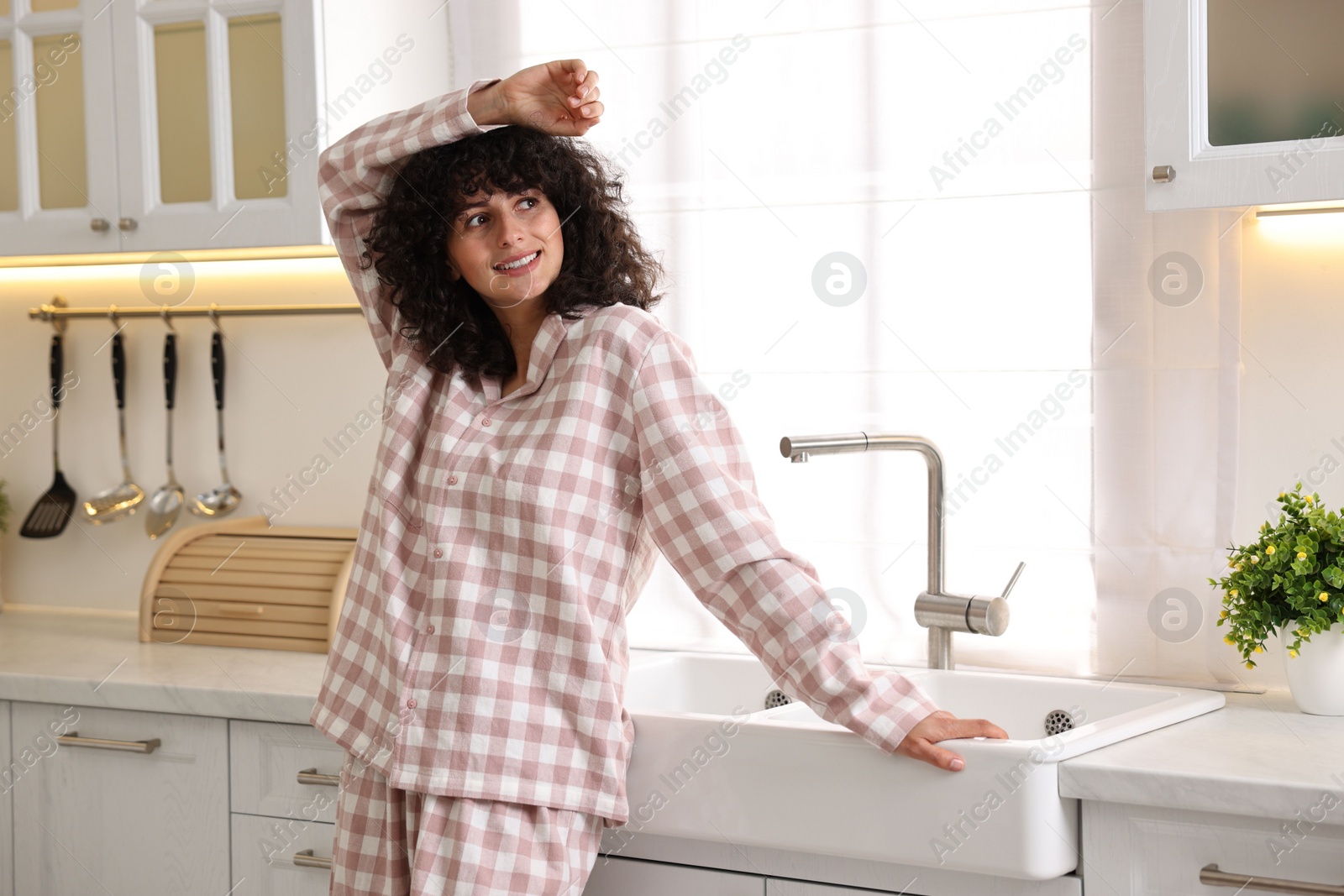 Photo of Beautiful young woman in stylish pyjama in kitchen