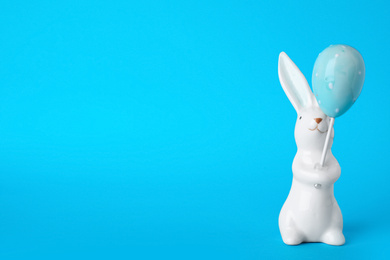 Photo of Bunny ceramic figure as Easter decor on blue background. Space for text