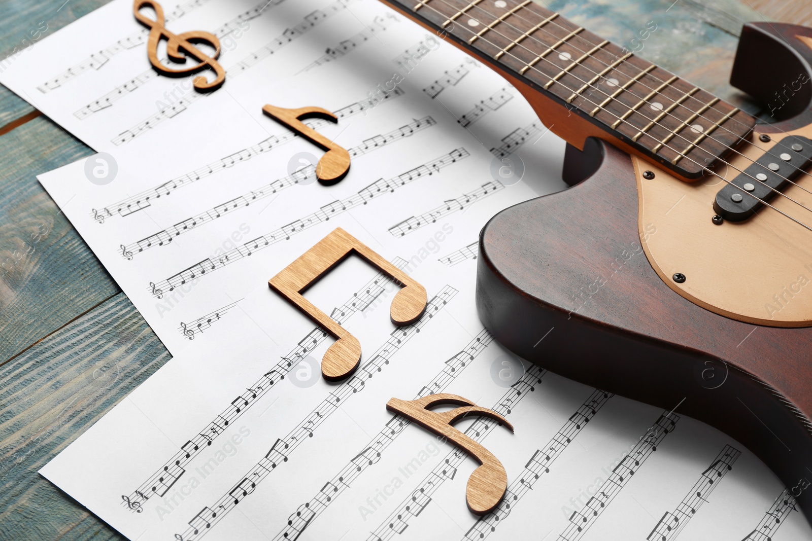 Photo of Guitar and sheets with music notes on wooden table