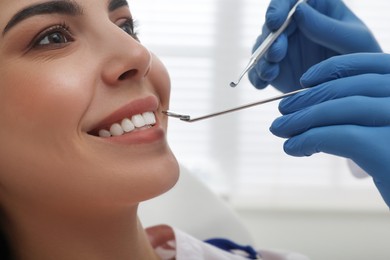 Photo of Dentist examining young woman's teeth in clinic, closeup