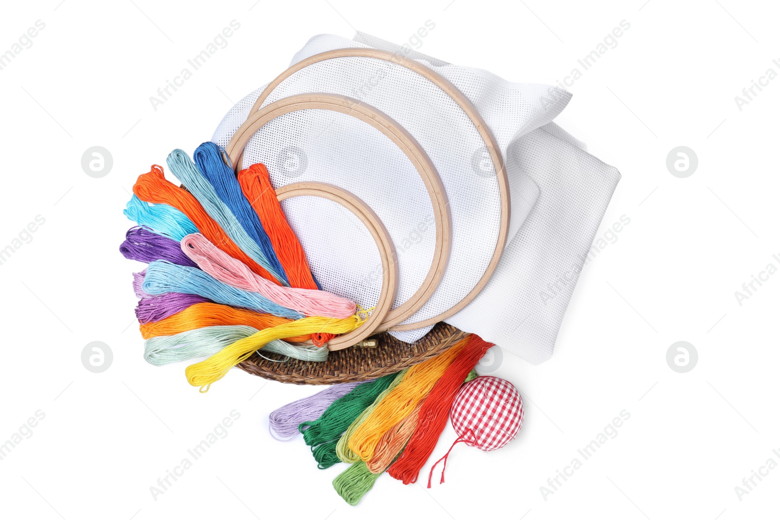 Photo of Colorful threads and different embroidery accessories on white background, top view