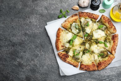 Photo of Delicious pizza with pesto, cheese and basil served on grey table, flat lay. Space for text
