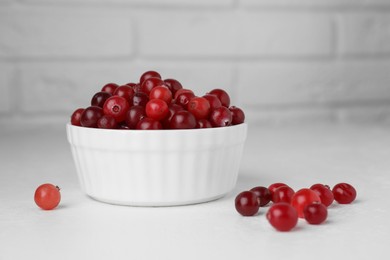 Photo of Ripe cranberries in bowl on white table