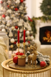 Photo of Christmas composition with decorative reindeer and candles on golden table in room