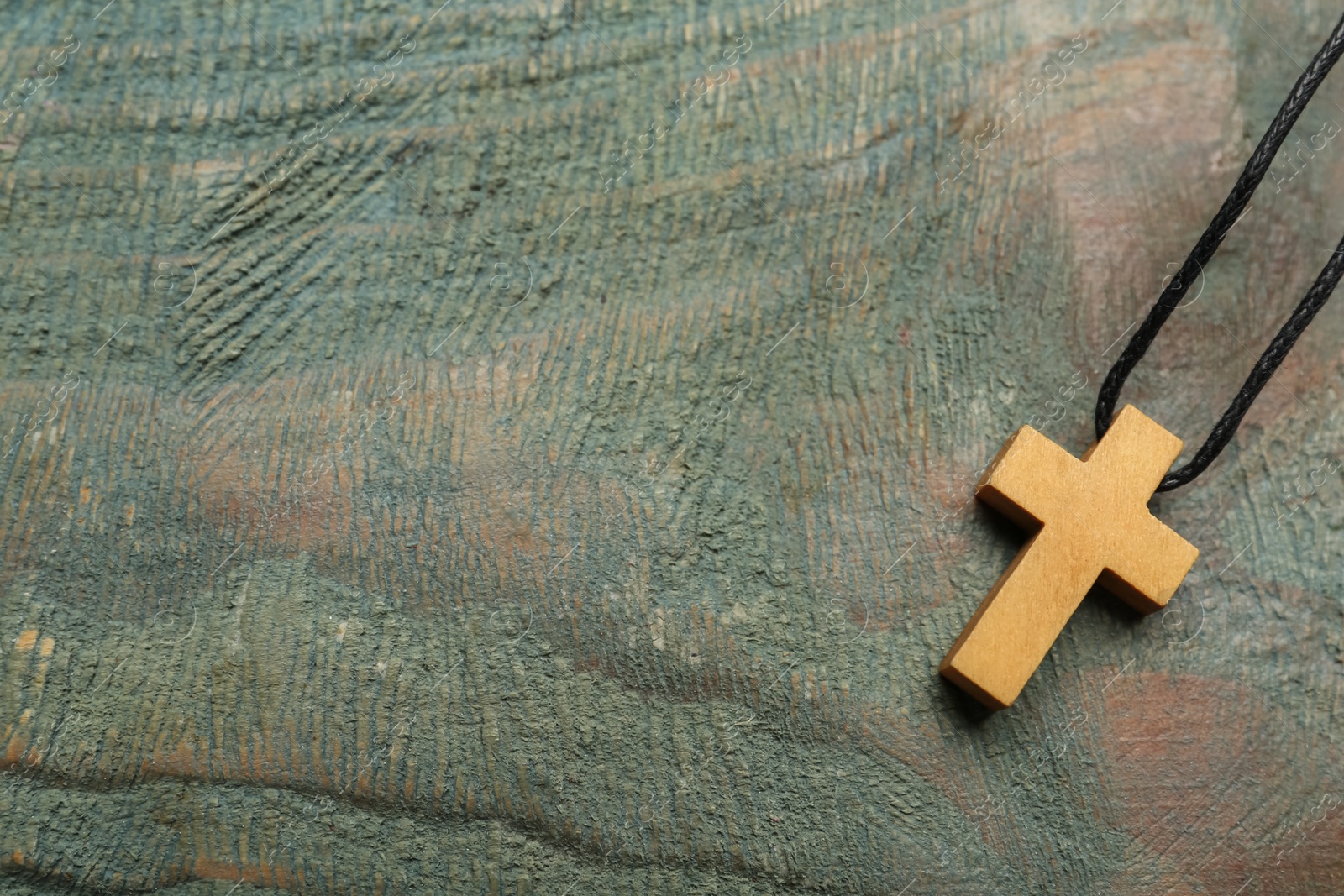 Photo of Christian cross on wooden table, top view. Space for text