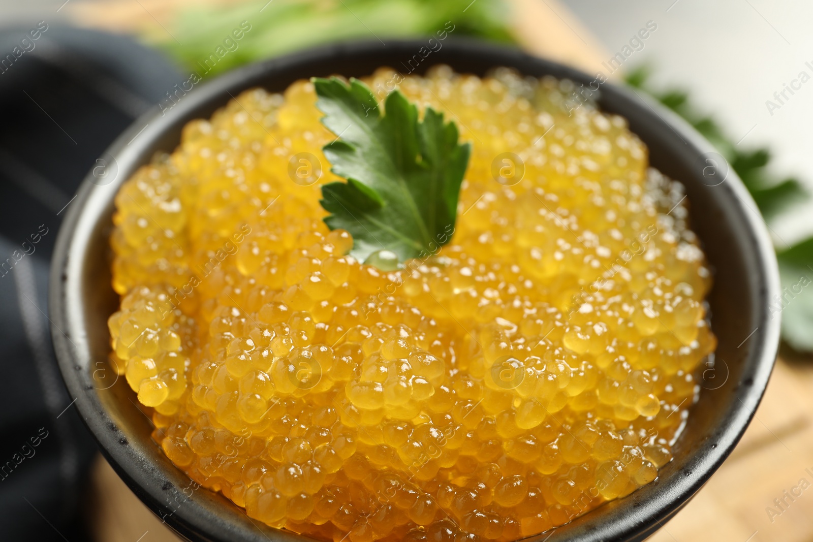 Photo of Fresh pike caviar and parsley in bowl on table, closeup