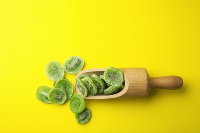 Photo of Scoop with slices of kiwi on color background, top view. Dried fruit as healthy food