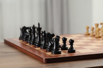 Photo of Chess board with black pieces on wooden table, closeup. Space for text