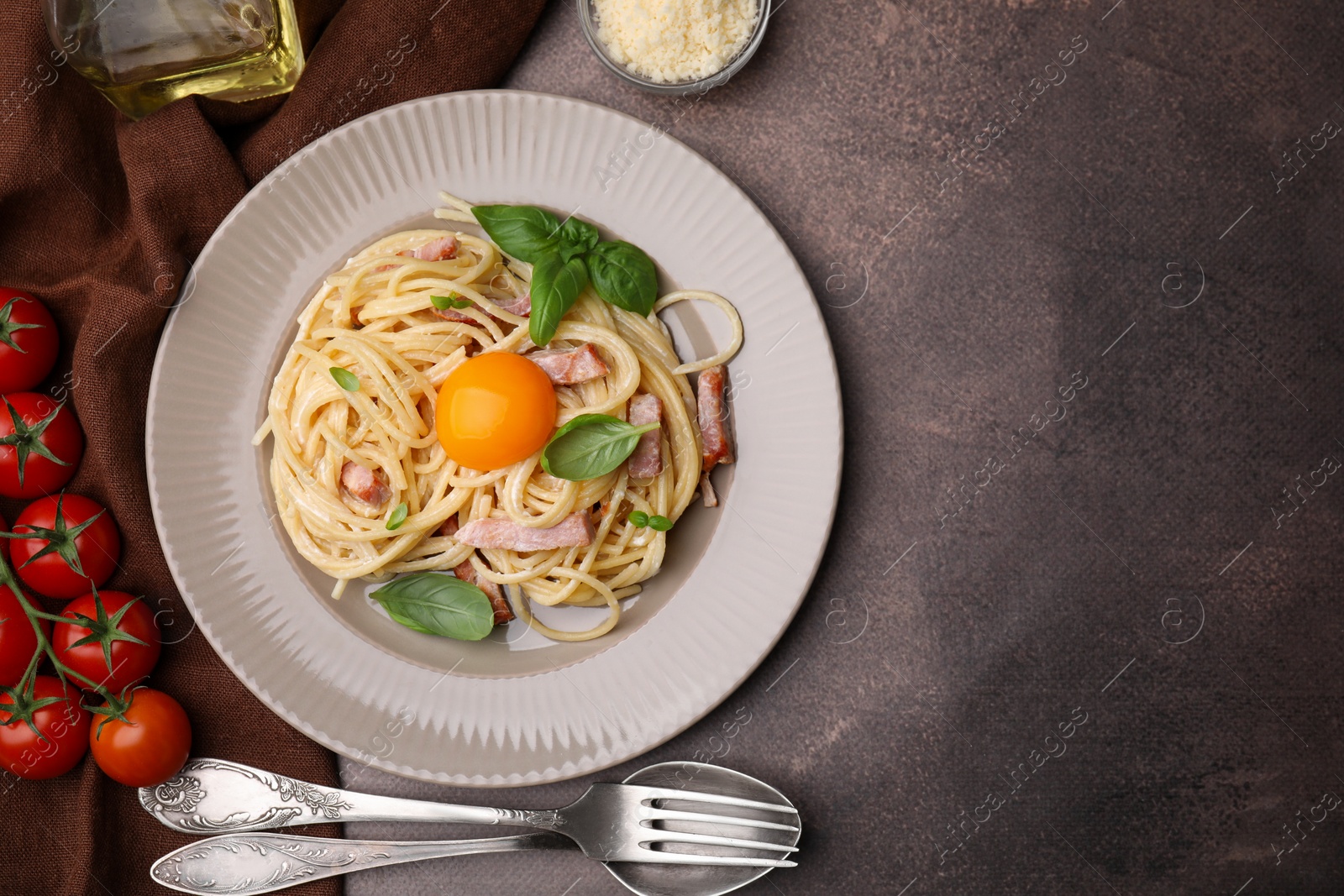 Photo of Delicious pasta Carbonara with egg yolk served on grey table, flat lay. Space for text