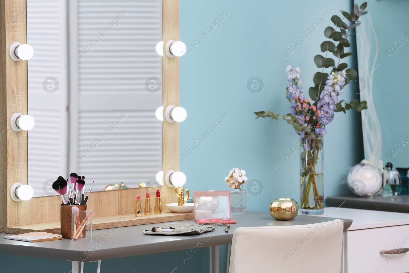 Photo of Decorative cosmetics and tools on dressing table near mirror in makeup room