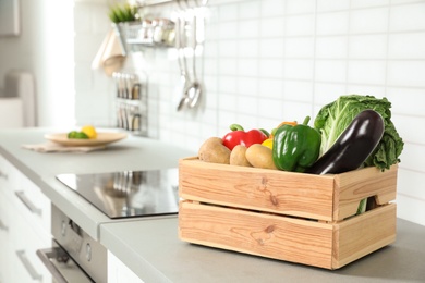 Photo of Wooden crate full of vegetables on countertop in kitchen. Space for text