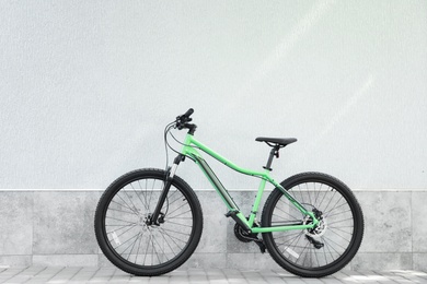 Photo of New modern color bicycle near light green wall outdoors