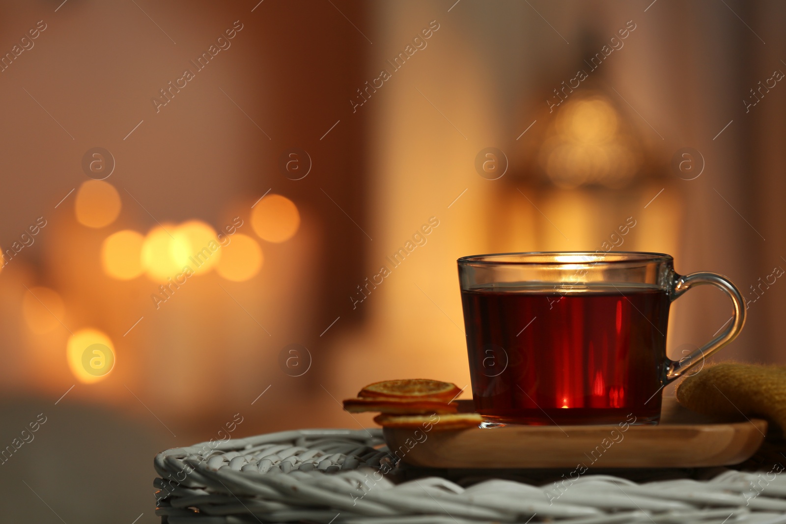 Photo of Cup of tea on table against blurred lights, space for text. Cozy winter