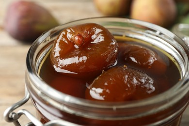 Photo of Jar of tasty sweet fig jam on table, closeup