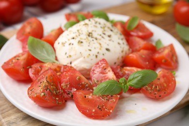 Photo of Tasty salad Caprese with mozarella, tomatoes and basil on wooden board, closeup