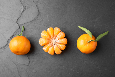 Photo of Fresh ripe tangerines on dark grey table, flat lay