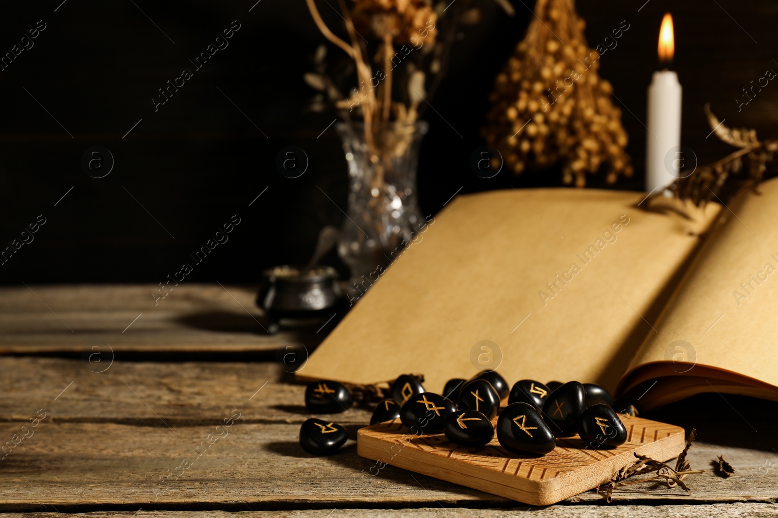 Photo of Composition with black rune stones and old book on wooden table. Space for text