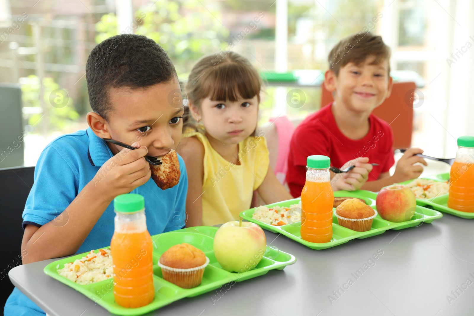 Photo of Children sitting at table and eating healthy food during break at school