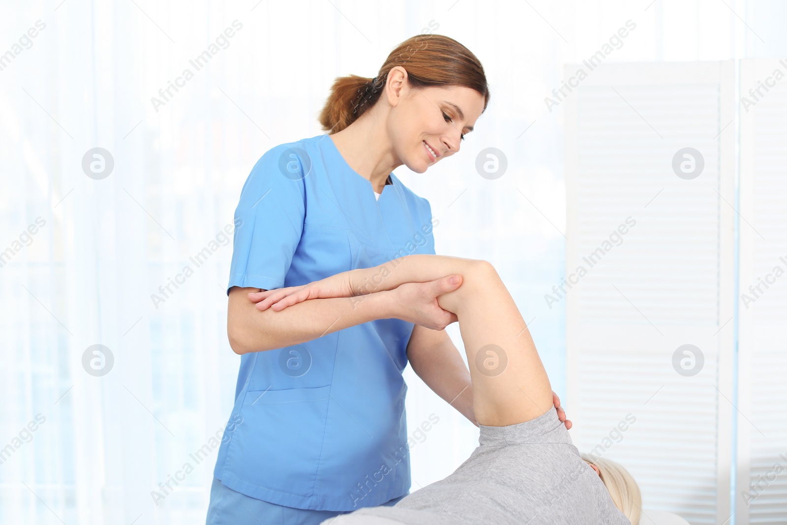 Photo of Physiotherapist working with patient in clinic. Rehabilitation therapy