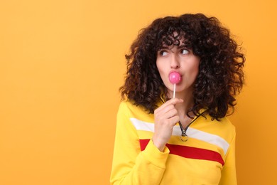 Photo of Beautiful woman with lollipop on yellow background, space for text