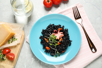 Delicious black risotto with seafood served on marble table, flat lay