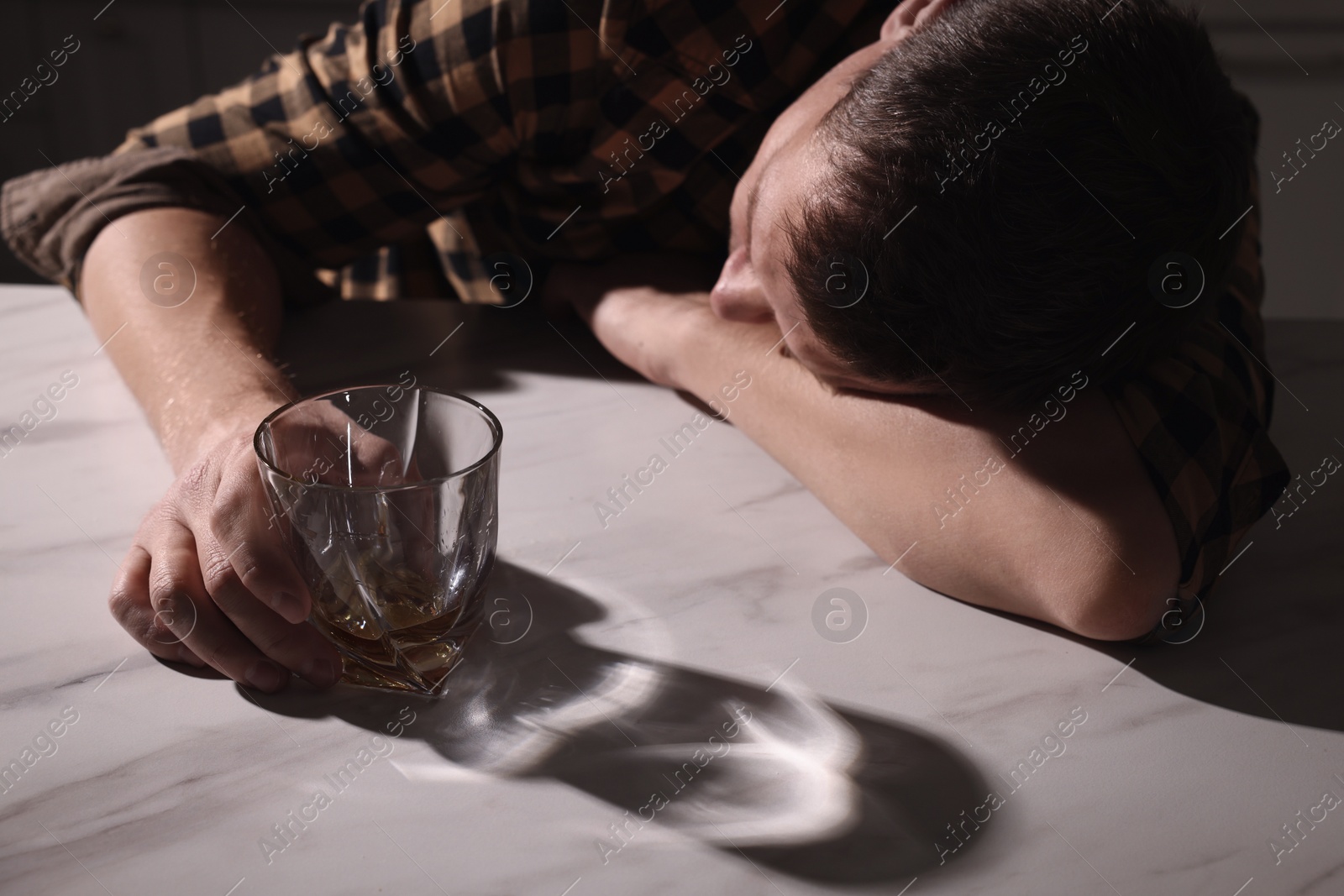 Photo of Addicted man with alcoholic drink sleeping at table in kitchen, closeup