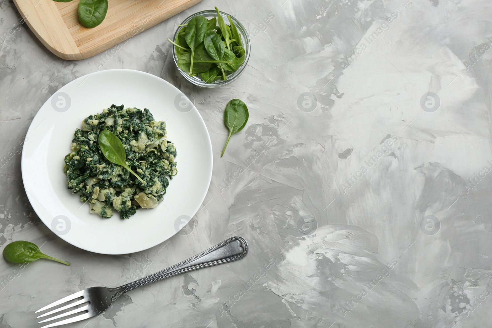 Photo of Flat lay composition with tasty spinach and space for text on grey table. Healthy food