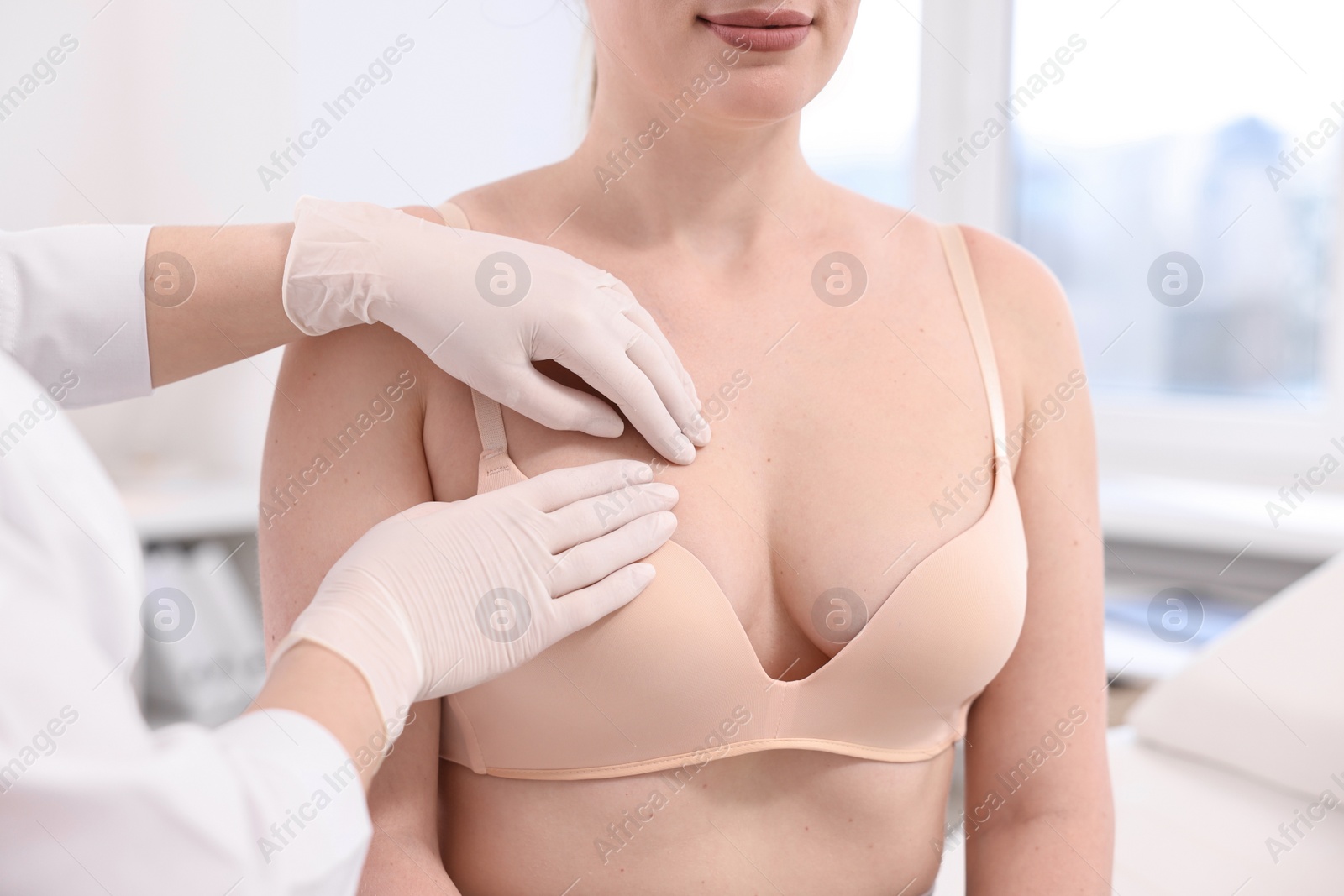 Photo of Mammologist checking woman's breast in hospital, closeup