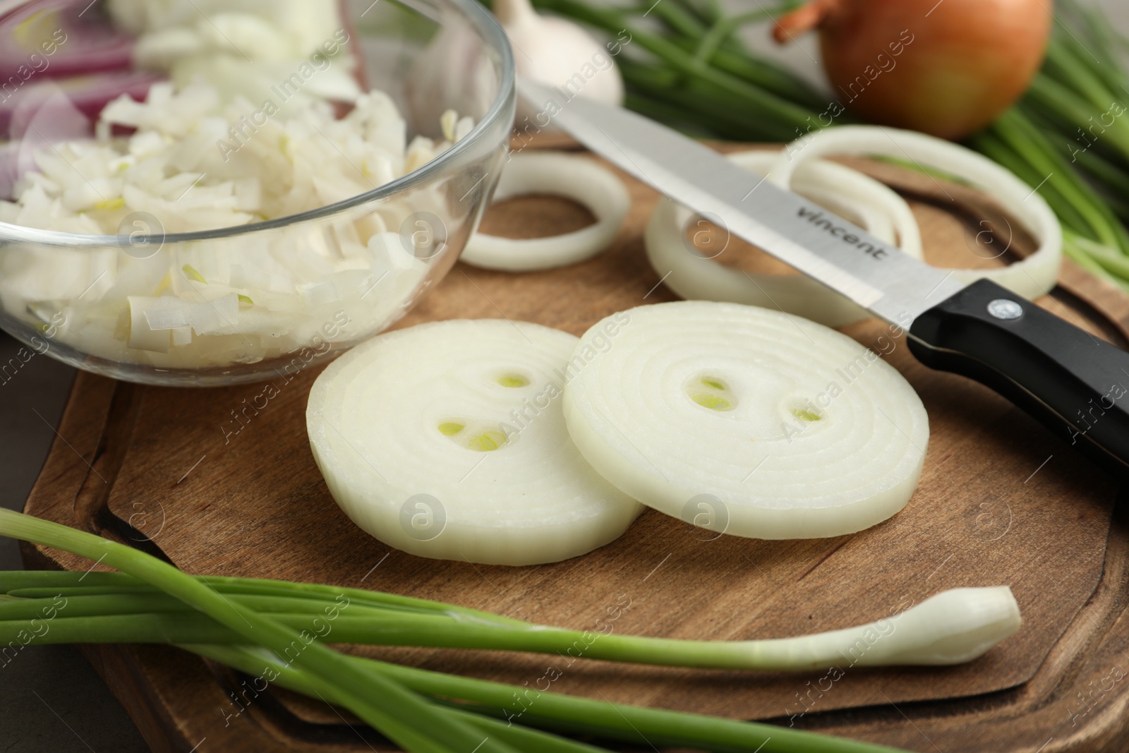 Photo of Fresh onion and knife on wooden board, closeup