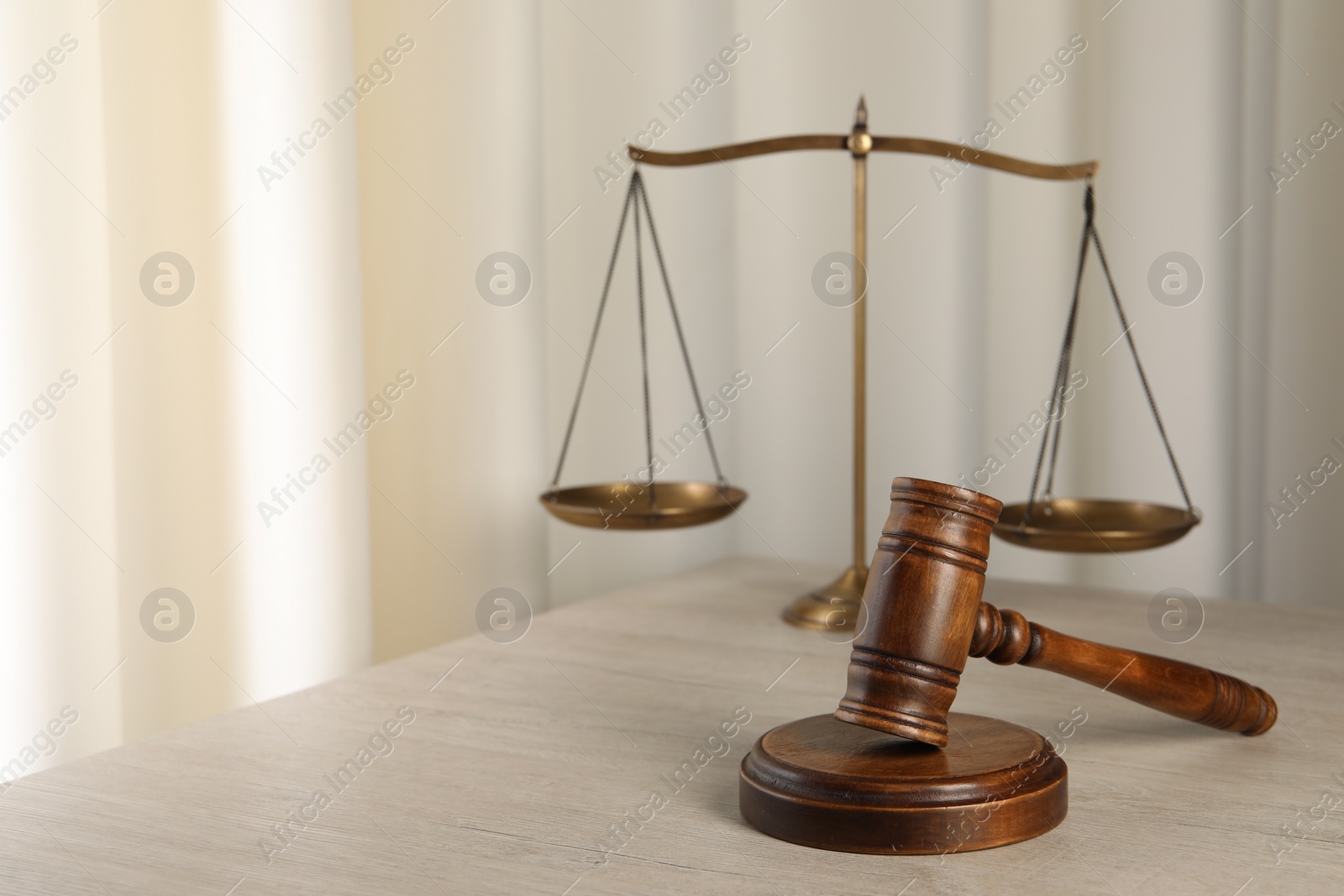 Photo of Law concept. Judge's mallet and scales of justice on light wooden table indoors, space for text