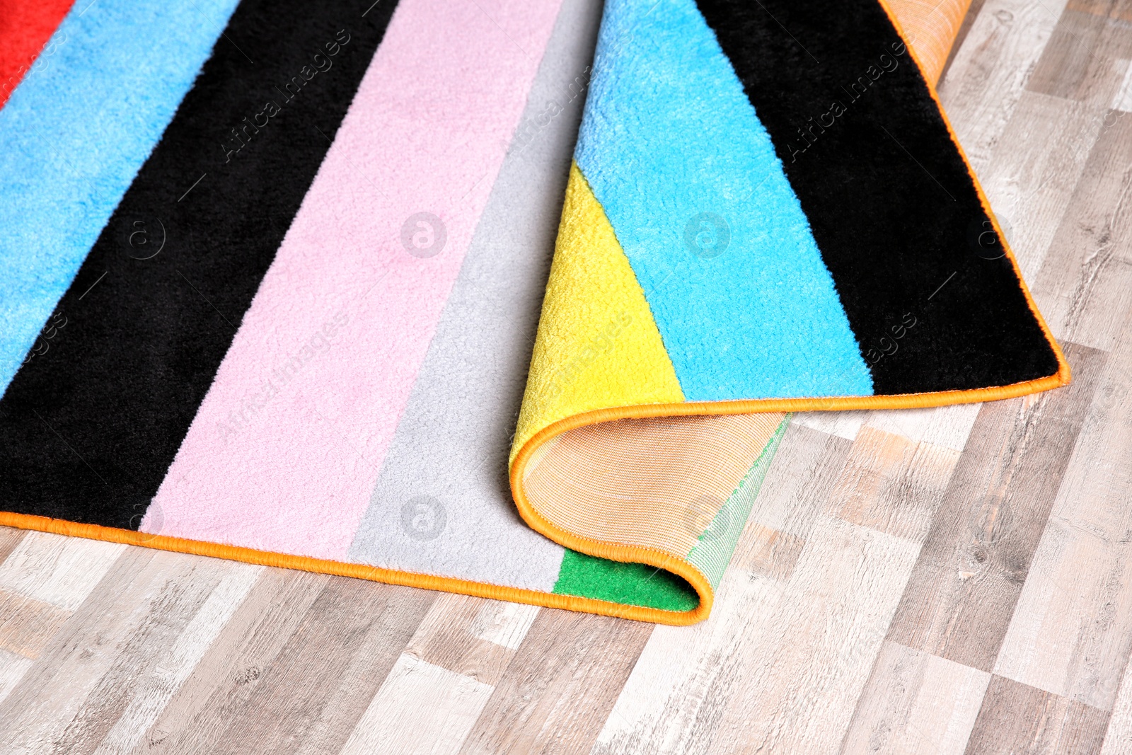 Photo of Colorful striped carpet on wooden floor