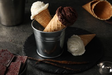 Photo of Ice cream scoops in wafer cones on gray textured table, closeup