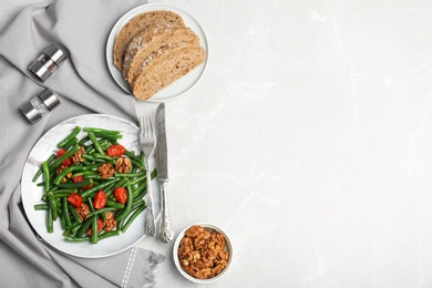 Photo of Tasty green beans with walnuts and tomatoes served for dinner on table, top view