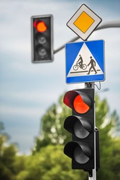 Post with Priority Road and Pedestrian crossing signs near traffic lights outdoors