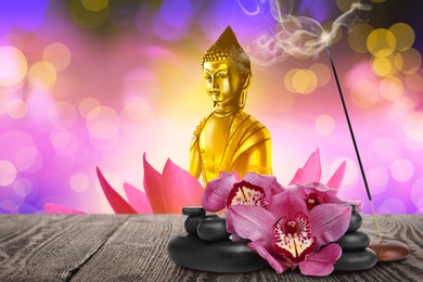 Composition with smoldering incense stick on wooden table and Buddha figure on background. Space for text