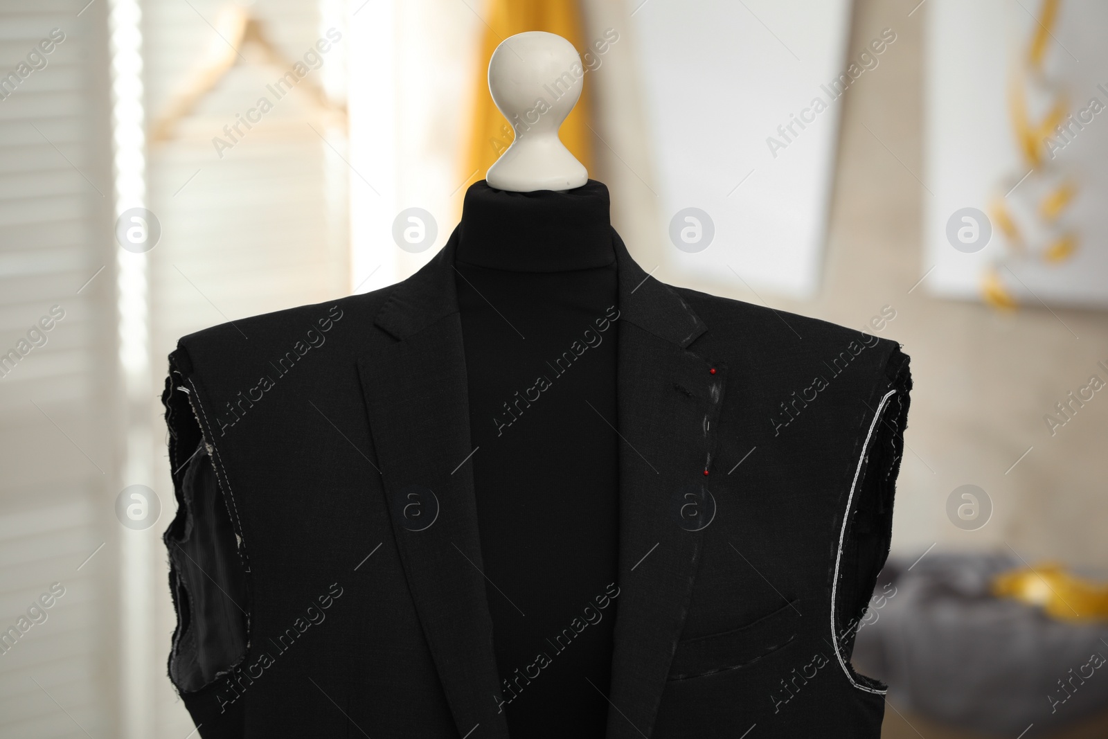 Photo of Mannequin with unfinished suit jacket in tailor shop, closeup