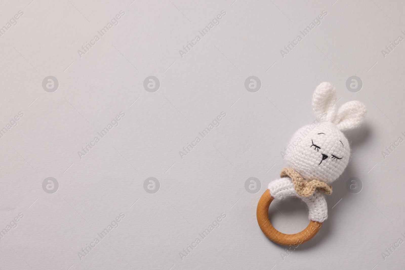Photo of Baby accessory. Rattle on grey background, top view. Space for text