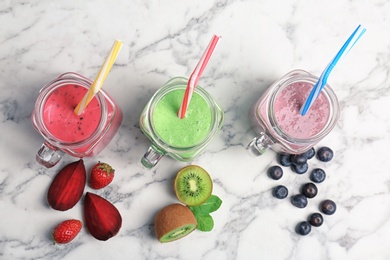 Photo of Mason jars with healthy detox smoothies and ingredients on marble background, top view