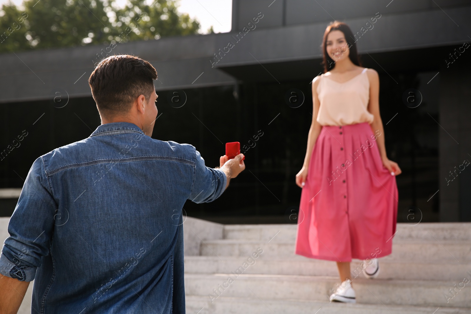 Photo of Man with engagement ring making proposal to his girlfriend outdoors