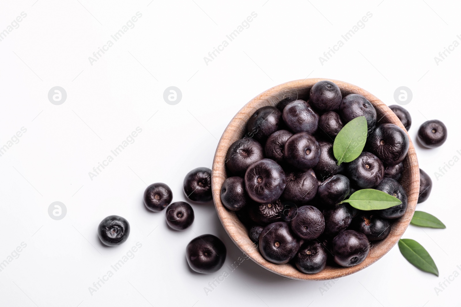 Photo of Bowl of fresh acai berries with leaves on white background, top view