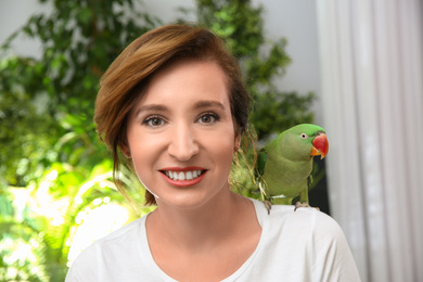 Photo of Happy woman with Alexandrine parakeet on blurred background