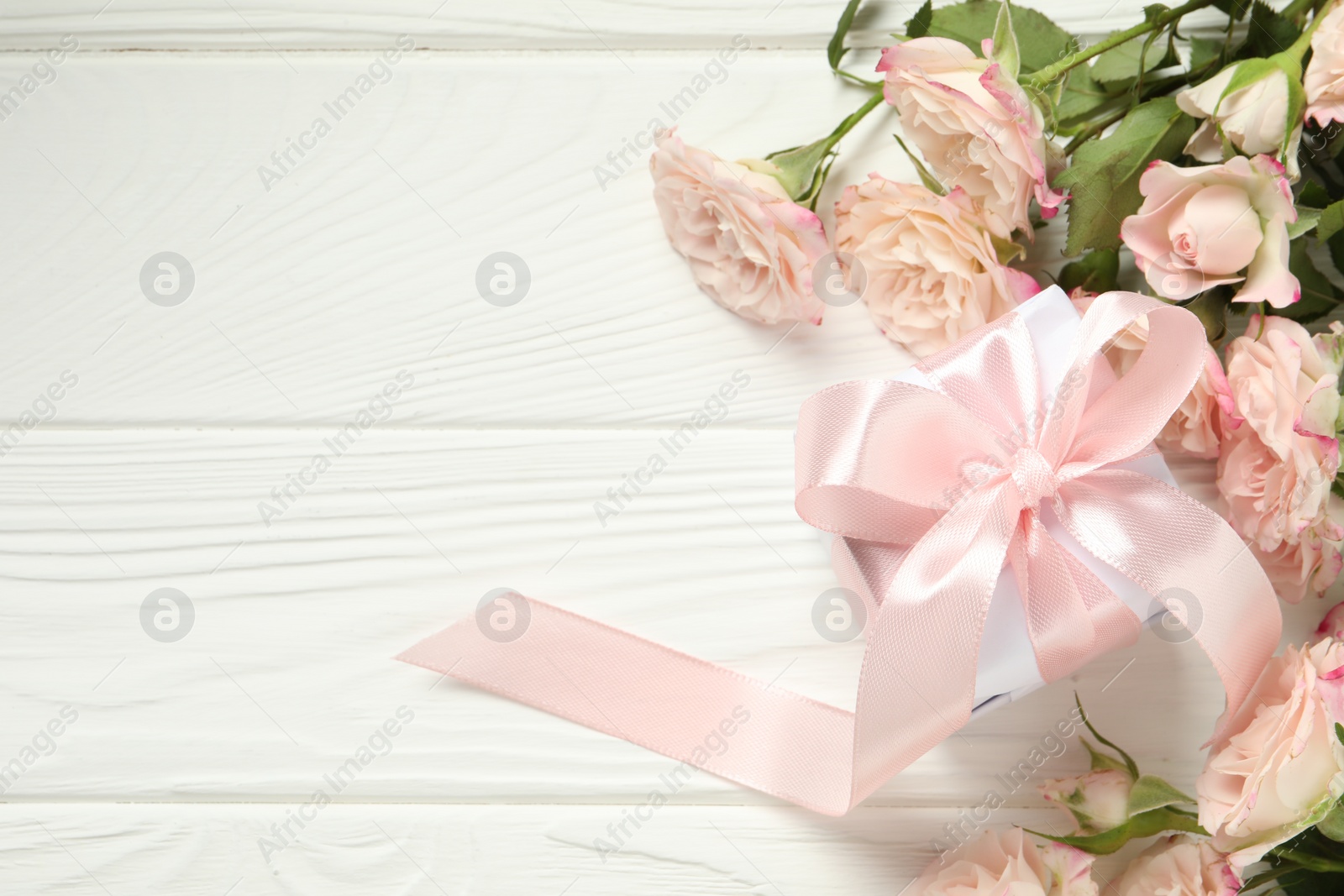 Photo of Happy Mother's Day. Beautiful roses and gift box on white wooden table, flat lay. Space for text