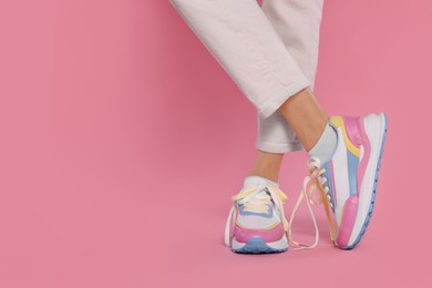 Woman wearing new stylish sneakers on pink background, closeup. Space for text