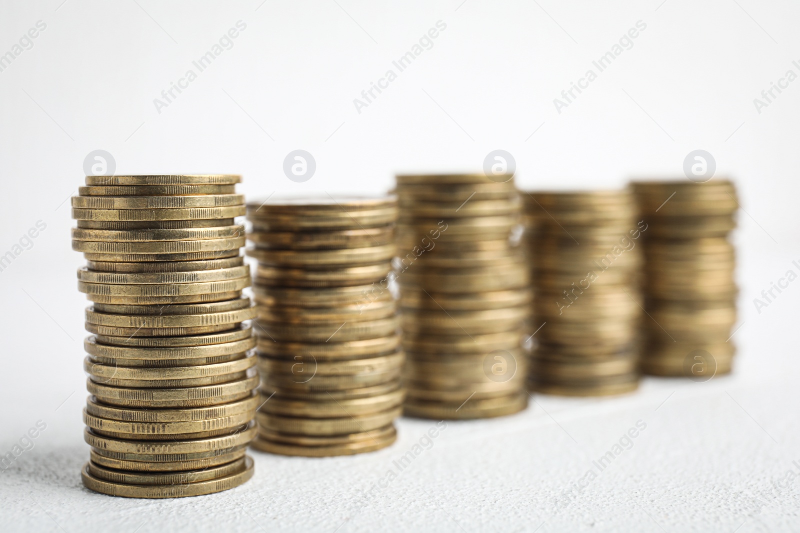 Photo of Many golden coins stacked on white table