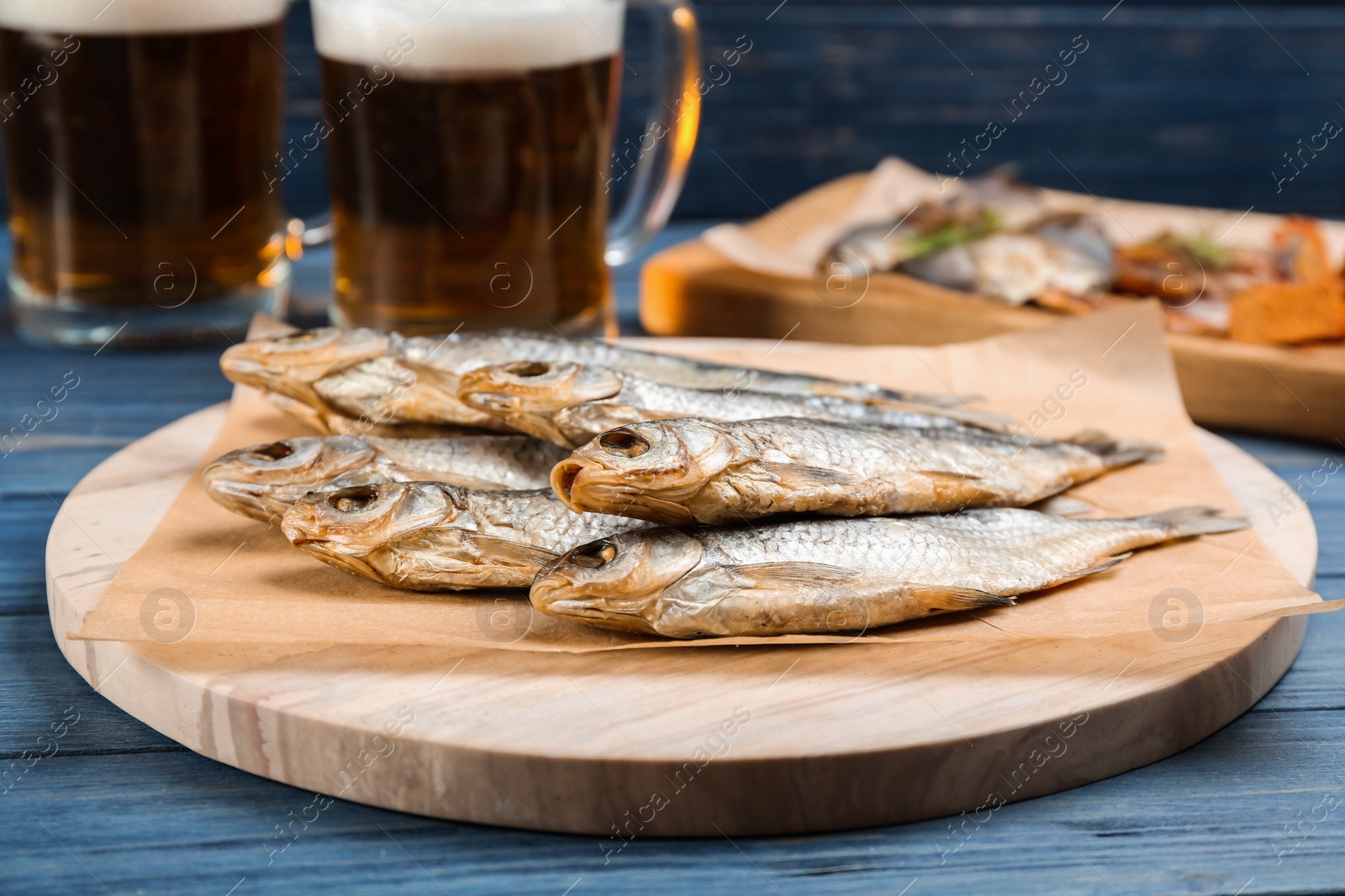 Photo of Tasty dried fish to beer on blue wooden table
