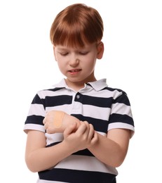 Little boy with sticking plaster on hand against light blue background
