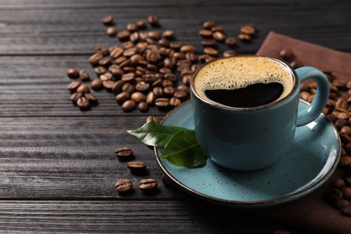 Cup of aromatic hot coffee and beans on black wooden table, space for text