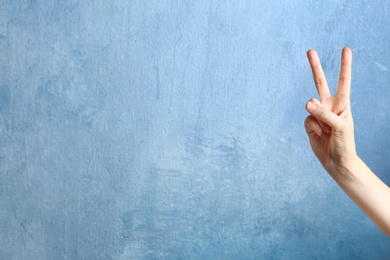 Photo of Woman showing victory sign on color background. Space for text